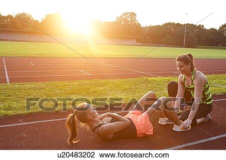 Two young women doing sit up training at race track View Large Photo Image Stock Image - Two young women doing sit up training at race track. Fotosearch