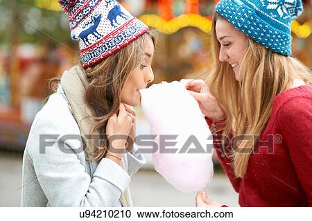 Two young women eating candy floss at funfair, outdoors View Large Photo Image Stock Image - Two young women eating candy floss at funfair, outdoors. Fotosearch