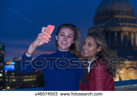 Two young women taking smartphone selfie in front of St Pauls at night, London, UK View Large Photo Image Stock Image - Two young women taking smartphone selfie in front of St Pauls at night, London, UK. Fotosearch