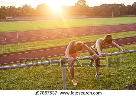 Stock Photo - Two young women training on handrail at race track. Fotosearch
