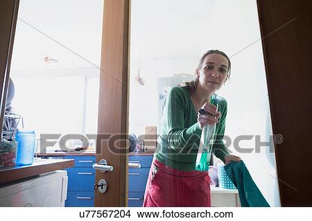 View through glass door of mid adult woman squirting cleaning product View Large Photo Image Picture - View through glass door of mid adult woman squirting cleaning product. Fotosearch