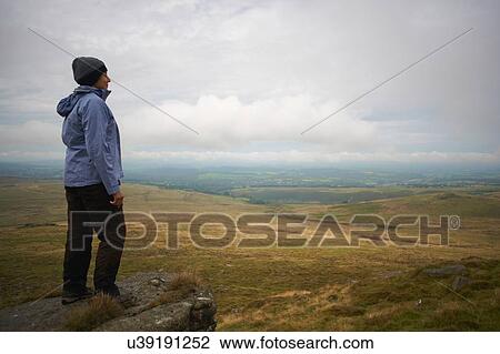 Stock Image - Woman enjoying view on rock formation, Dartmoor, Devon, UK. Fotosearch
