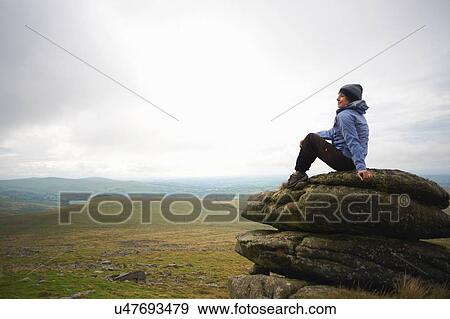 Stock Photo - Woman enjoying view on rock formation, Dartmoor, Devon, UK. Fotosearch