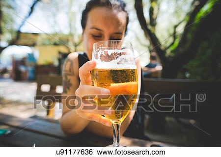 Woman holding up glass of beer, Garda, Italy View Large Photo Image Stock Photograph - Woman holding up glass of beer, Garda, Italy. Fotosearch