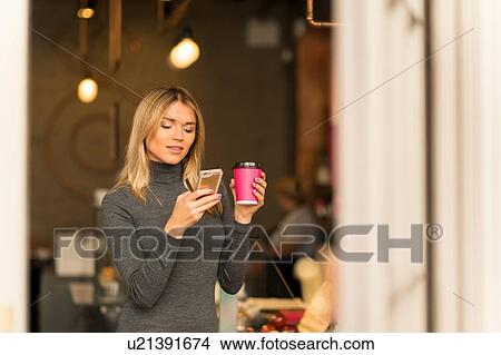 Woman with takeaway coffee using smartphone View Large Photo Image Picture - Woman with takeaway coffee using smartphone. Fotosearch