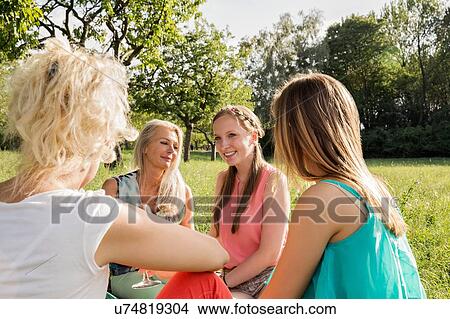 Women sitting in park drinking wine, talking and smiling View Large Photo Image Picture - Women sitting in park drinking wine, talking and smiling. Fotosearch