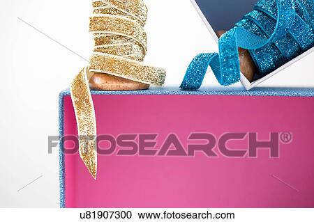Wooden reel of sparkly blue and gold ribbon on top of pink gift box View Large Photo Image Stock Image - Wooden reel of sparkly blue and gold ribbon on top of pink gift box. Fotosearch