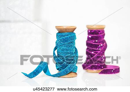 Stock Photo - Wooden reels of sparkly blue and purple ribbon. Fotosearch