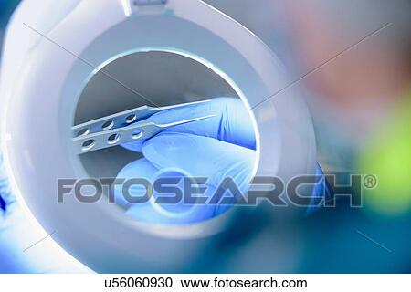 Stock Image - Worker inspecting surgical instruments in clean room of surgical instruments factory, close up. Fotosearch