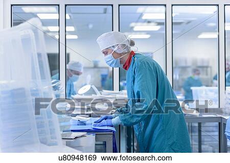 Stock Photo - Worker inspecting surgical instruments in clean room of surgical instruments factory. Fotosearch