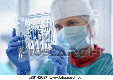 Stock Photo - Worker inspecting surgical instruments in clean room of surgical instruments factory, close up. Fotosearch