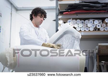 Stock Image - Worker preparing mould for orthopaedic support in factory. Fotosearch
