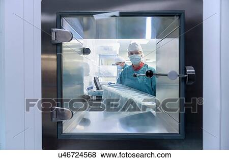 Stock Photo - Worker putting surgical instruments into air lock in clean room of surgical instruments factory. Fotosearch