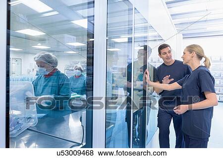 Stock Photo - Workers in discussion outside clean room in surgical instrument factory. Fotosearch