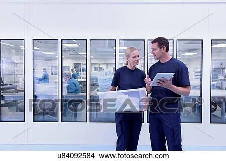 Workers with digital tablet inspecting products outside clean room in surgical instrument factory View Large Photo Image Picture - Workers with digital tablet inspecting products outside clean room in surgical instrument factory. Fotosearch
