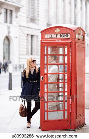 Stock Photograph - Young couple in red phone box, London, England, UK. Fotosearch