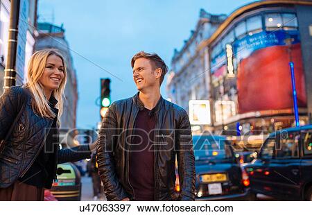 Stock Photo - Young couple on city street at night, London, England, UK. Fotosearch