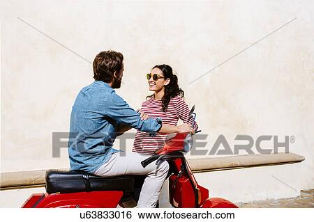 Stock Photograph - Young couple on moped chatting, Florence, Italy. Fotosearch