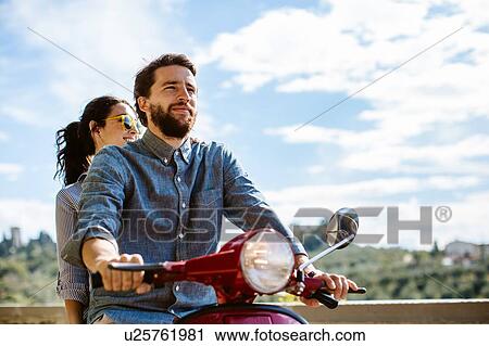 Stock Image - Young couple riding moped in Florence hills, Italy. Fotosearch