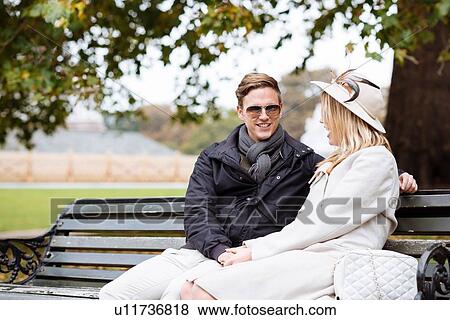 Young couple sitting on park bench, London, England, UK View Large Photo Image Stock Photo - Young couple sitting on park bench, London, England, UK. Fotosearch