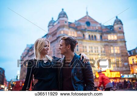 Stock Photo - Young couple strolling on city street at night, London, England, UK. Fotosearch