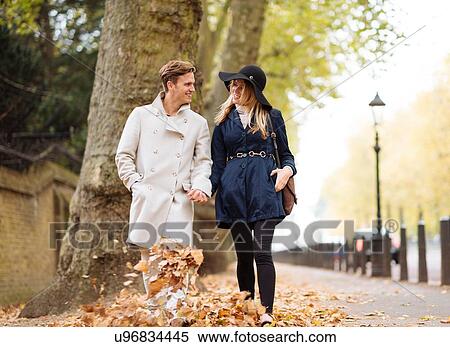 Stock Photography - Young couple strolling through autumn leaves, London, England, UK. Fotosearch