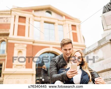 Stock Photography - Young couple taking smartphone selfie outside Albert Hall, London, England, UK. Fotosearch