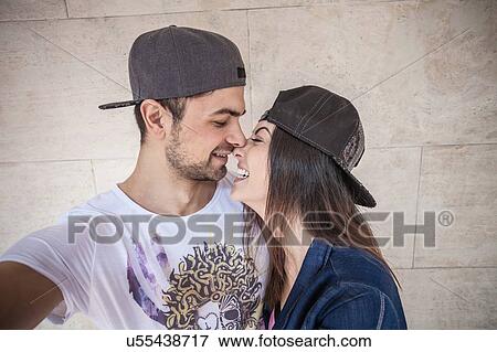 Stock Photo - Young couple wearing cap, in loving embrace. Fotosearch