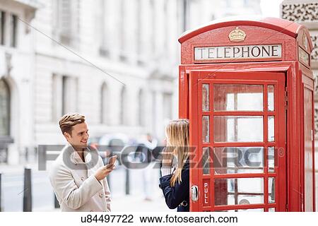 Young couple with smartphone next to red phone box, London, England, UK View Large Photo Image Stock Image - Young couple with smartphone next to red phone box, London, England, UK. Fotosearch