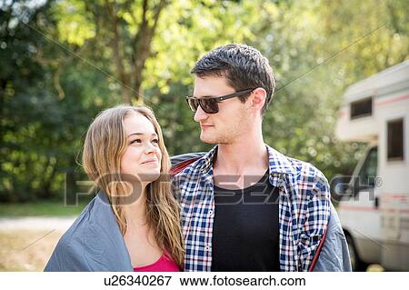 Young couple wrapped in blanket, outdoors, face to face, smiling View Large Photo Image Stock Photo - Young couple wrapped in blanket, outdoors, face to face, smiling. Fotosearch