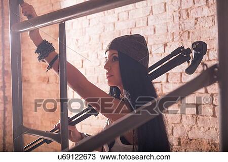 Stock Image - Young female photographer preparing scaffolding in old industrial building. Fotosearch