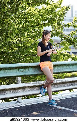 Stock Image - Young female runner checking smartwatch. Fotosearch