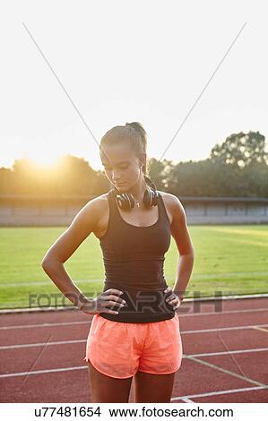 Picture - Young female runner on race track with hands on hips. Fotosearch