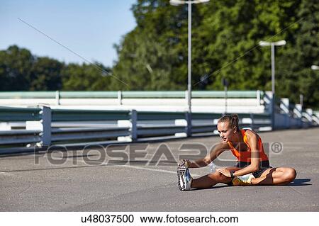 Young female runner touching toes in parking lot View Large Photo Image Stock Image - Young female runner touching toes in parking lot. Fotosearch