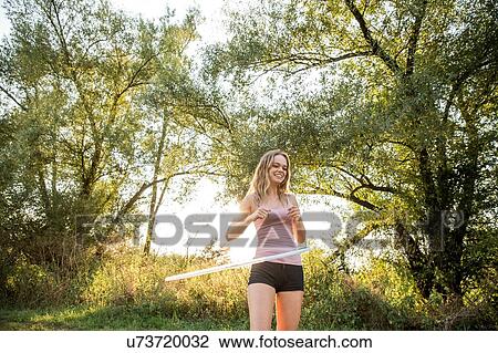 Young girl in rural environment, using hula hoop, smiling View Large Photo Image Stock Image - Young girl in rural environment, using hula hoop, smiling. Fotosearch