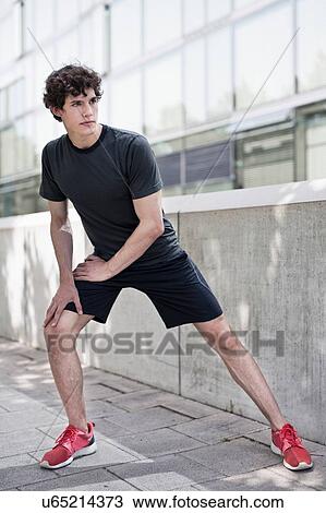 Young male runner doing warm up stretches on sidewalk View Large Photo Image Stock Image - Young male runner doing warm up stretches on sidewalk. Fotosearch