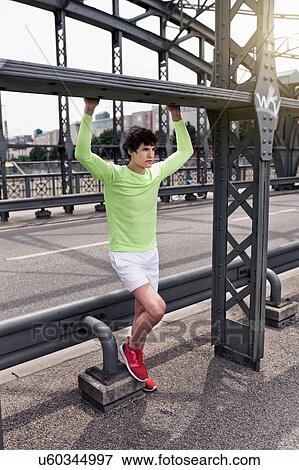 Young male runner holding girder on urban bridge View Large Photo Image Stock Photo - Young male runner holding girder on urban bridge. Fotosearch