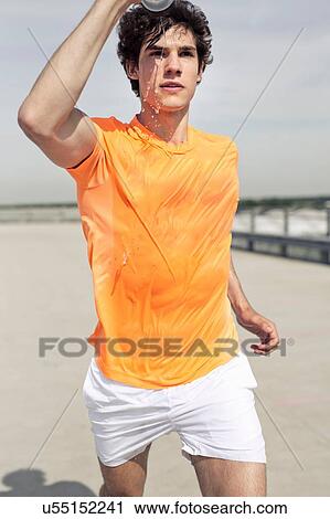 Young male runner pouring water on his face whilst city running View Large Photo Image Stock Image - Young male runner pouring water on his face whilst city running. Fotosearch