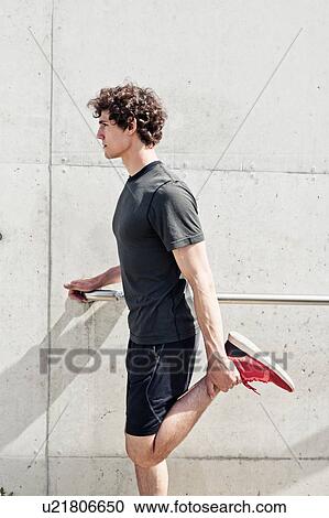 Young male runner stretching legs in city View Large Photo Image Stock Image - Young male runner stretching legs in city. Fotosearch