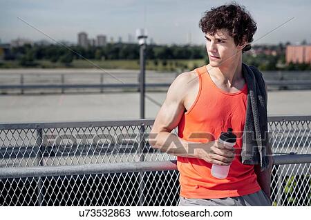 Young male runner with water bottle looking over his shoulder in city View Large Photo Image Stock Image - Young male runner with water bottle looking over his shoulder in city. Fotosearch