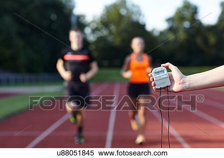 Stock Photography - Young man and woman running on race track against stopwatch. Fotosearch