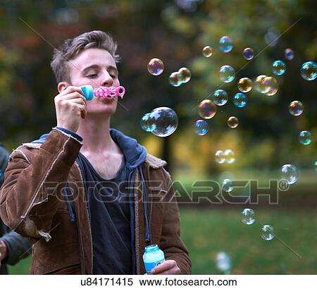 Stock Photography - Young man blowing bubbles in autumn park. Fotosearch