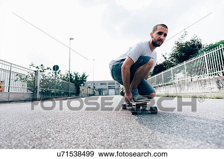 Young man crouched on skateboard View Large Photo Image Stock Photo - Young man crouched on skateboard. Fotosearch
