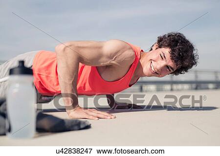Stock Photo - Young man doing training push ups in city. Fotosearch