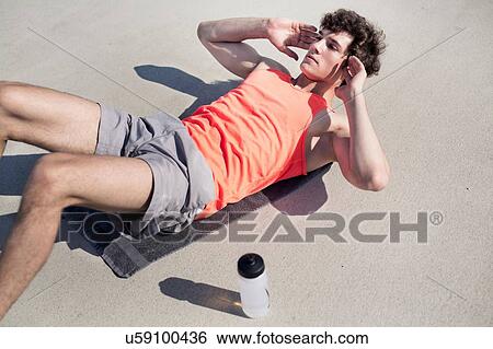 Young man doing training sit ups in city View Large Photo Image Stock Photograph - Young man doing training sit ups in city. Fotosearch