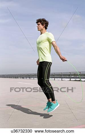 Stock Image - Young man exercising with skipping ropes in city. Fotosearch