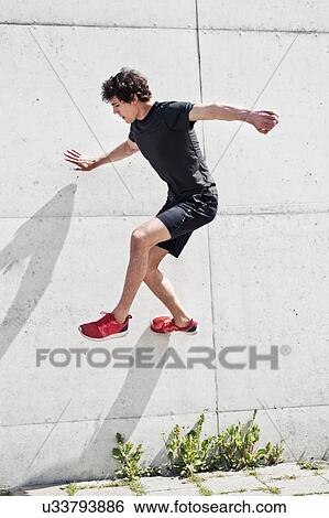 Stock Photograph - Young man free running against concrete wall. Fotosearch