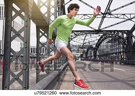 Stock Image - Young man free running on urban bridge. Fotosearch