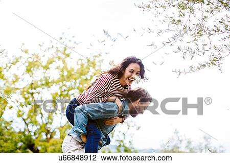 Young man giving girlfriend a piggy back in olive grove, Florence, Italy View Large Photo Image Stock Image - Young man giving girlfriend a piggy back in olive grove, Florence, Italy. Fotosearch
