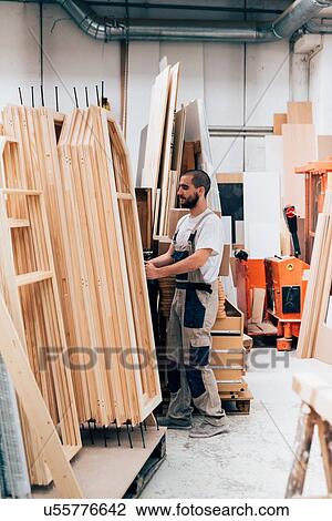 Young man in carpentry workshop stacking timber construction frames View Large Photo Image Stock Image - Young man in carpentry workshop stacking timber construction frames. Fotosearch